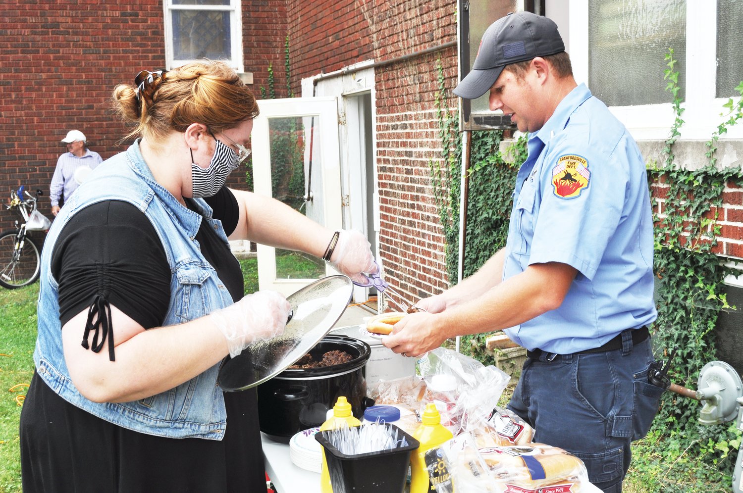 Praise Sharp dishes up a hot dog for CJ Mullett of the Crawfordsville Fire/EMS Department Saturday at The Pentecostals of Crawfordsville. To recognize the 19th anniversary of the Sept. 11 attacks, the church held a cookout for local first responders and military personnel.